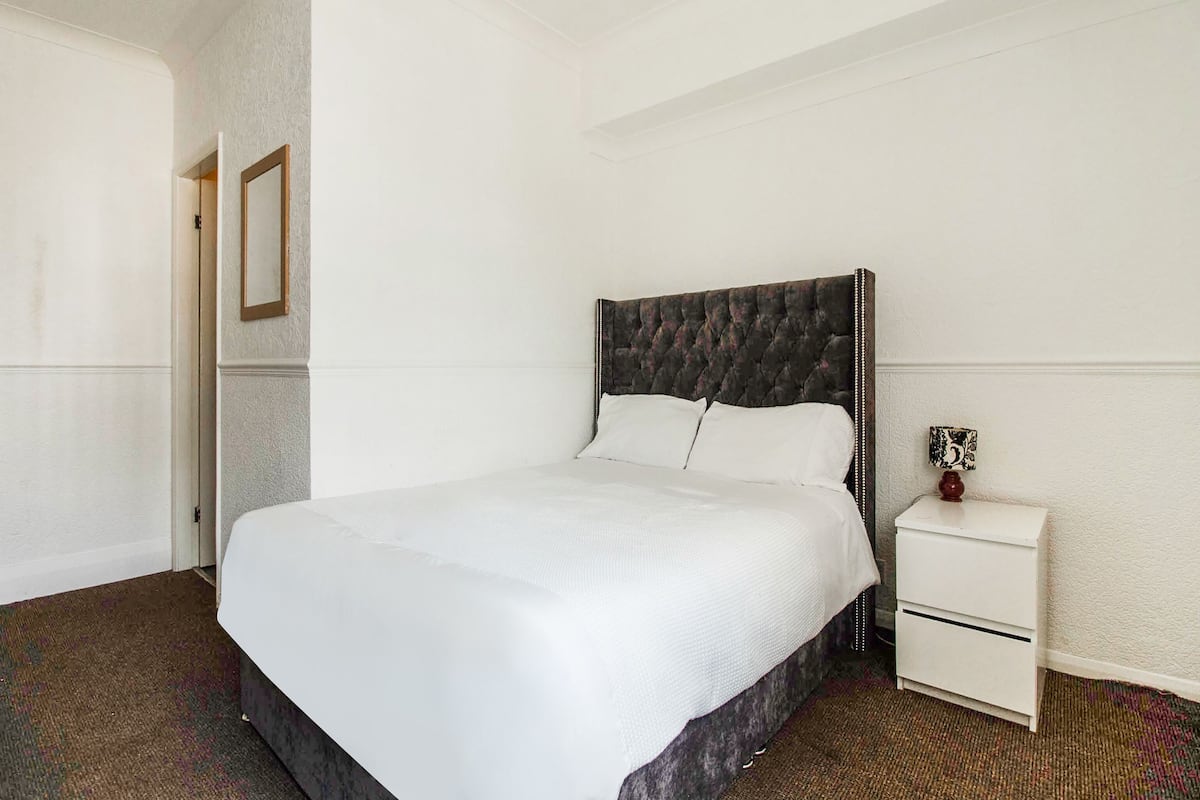 A neatly arranged bedroom with a large bed, a bedside table, and a small cabinet.