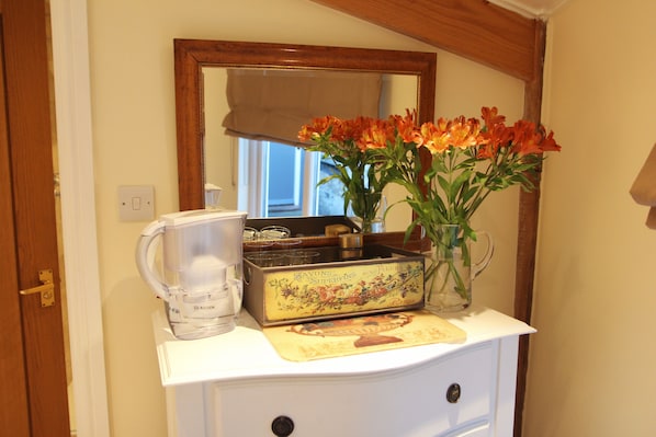 A kitchen counter with a coffee maker, a decorative box, and a vase with flowers. - Croft House Guest Suite (Stroud)