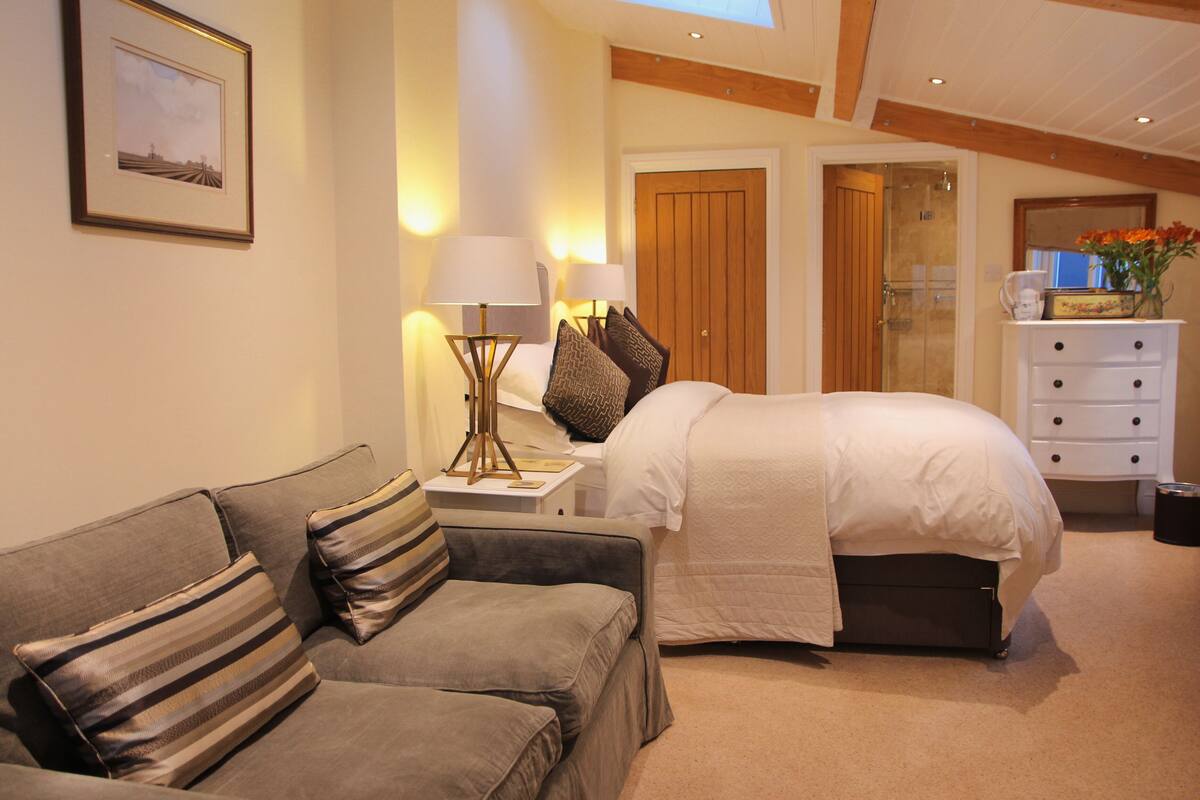 A bedroom with a bed, a nightstand, a lamp, a dresser, and a framed picture on the wall.