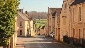 A narrow street lined with stone buildings, a clear sky, and a distant view of green fields. - Croft House Guest Suite (Stroud)