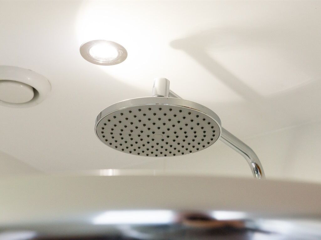 Un cabezal de ducha con diseño circular e iluminación separada arriba.