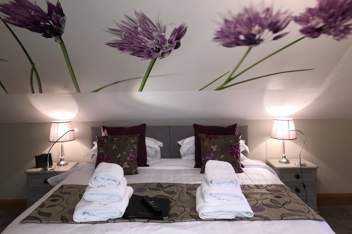 A hotel room with a bed, two nightstands, lamps, and a wall with floral wallpaper.