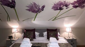 A hotel room with a bed, two nightstands, lamps, and a wall with floral wallpaper.