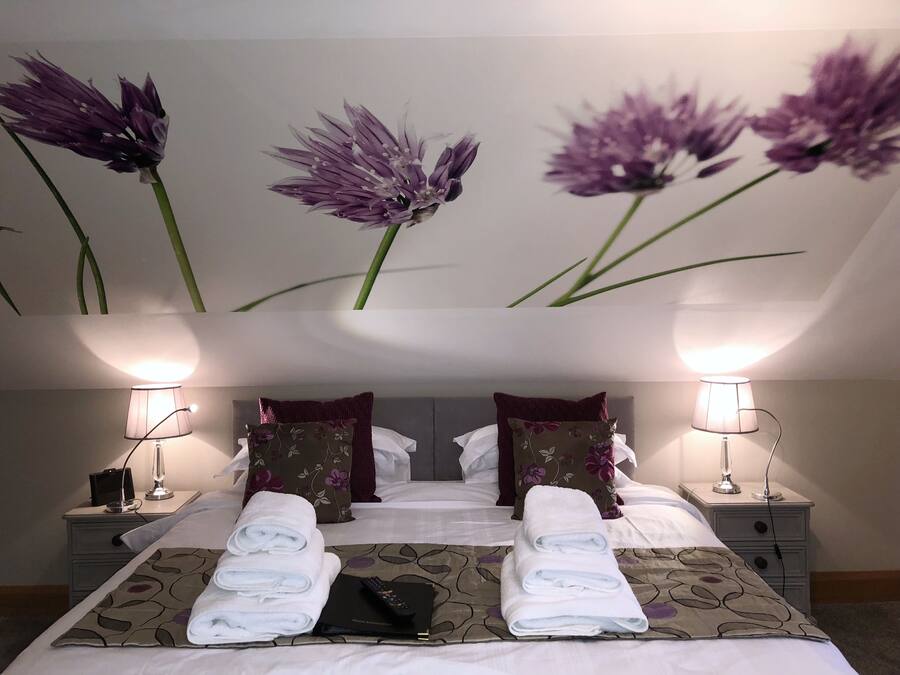 A hotel room with a bed, two nightstands, lamps, and a wall with floral wallpaper.