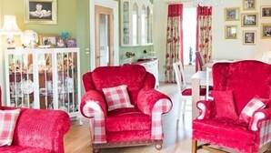 A room with a red armchair, a matching sofa, and a white cabinet with glass doors. - Ashbrook House B&B (Dungannon)