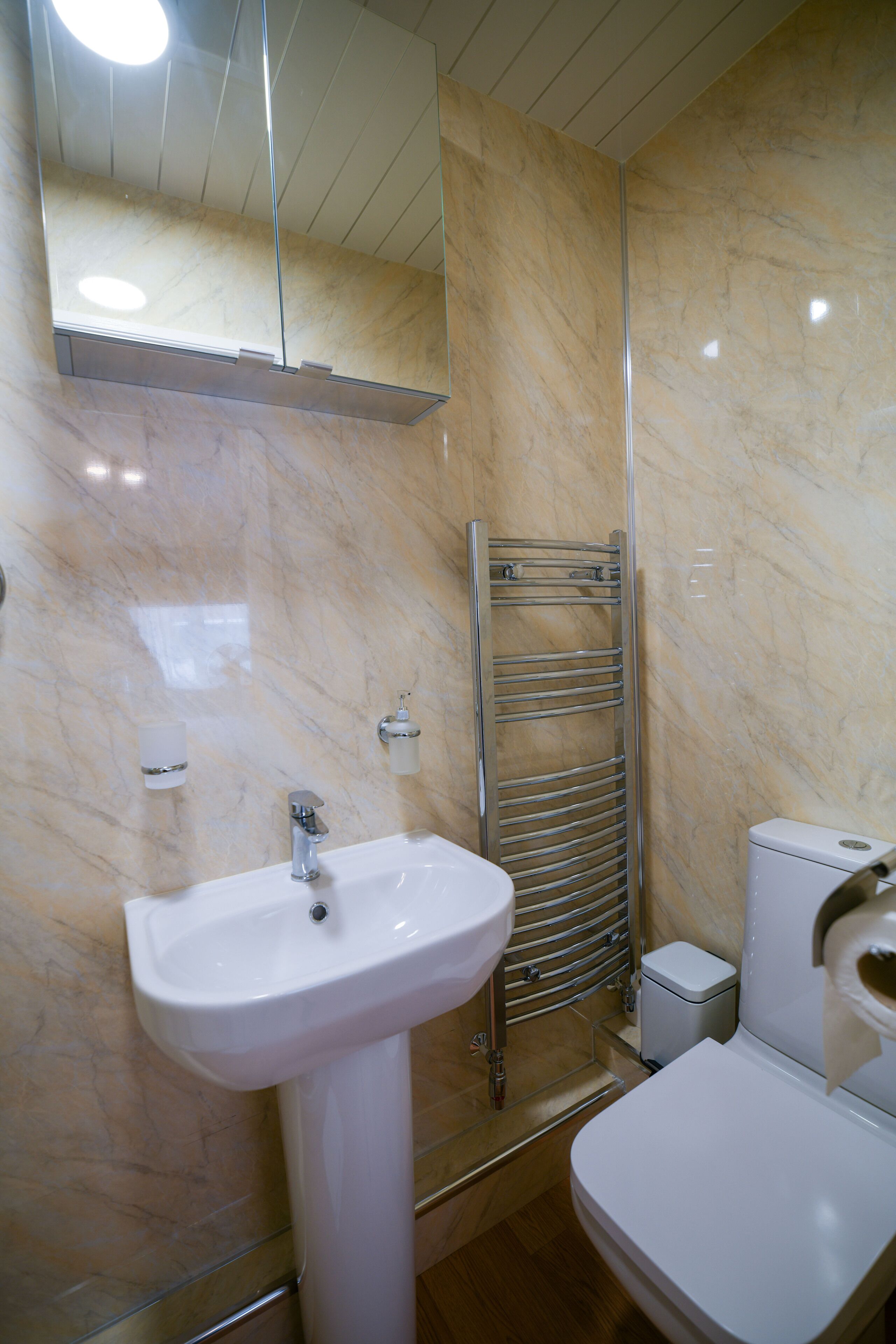 A bathroom with a white sink, a toilet, a towel rack, and a mirror.