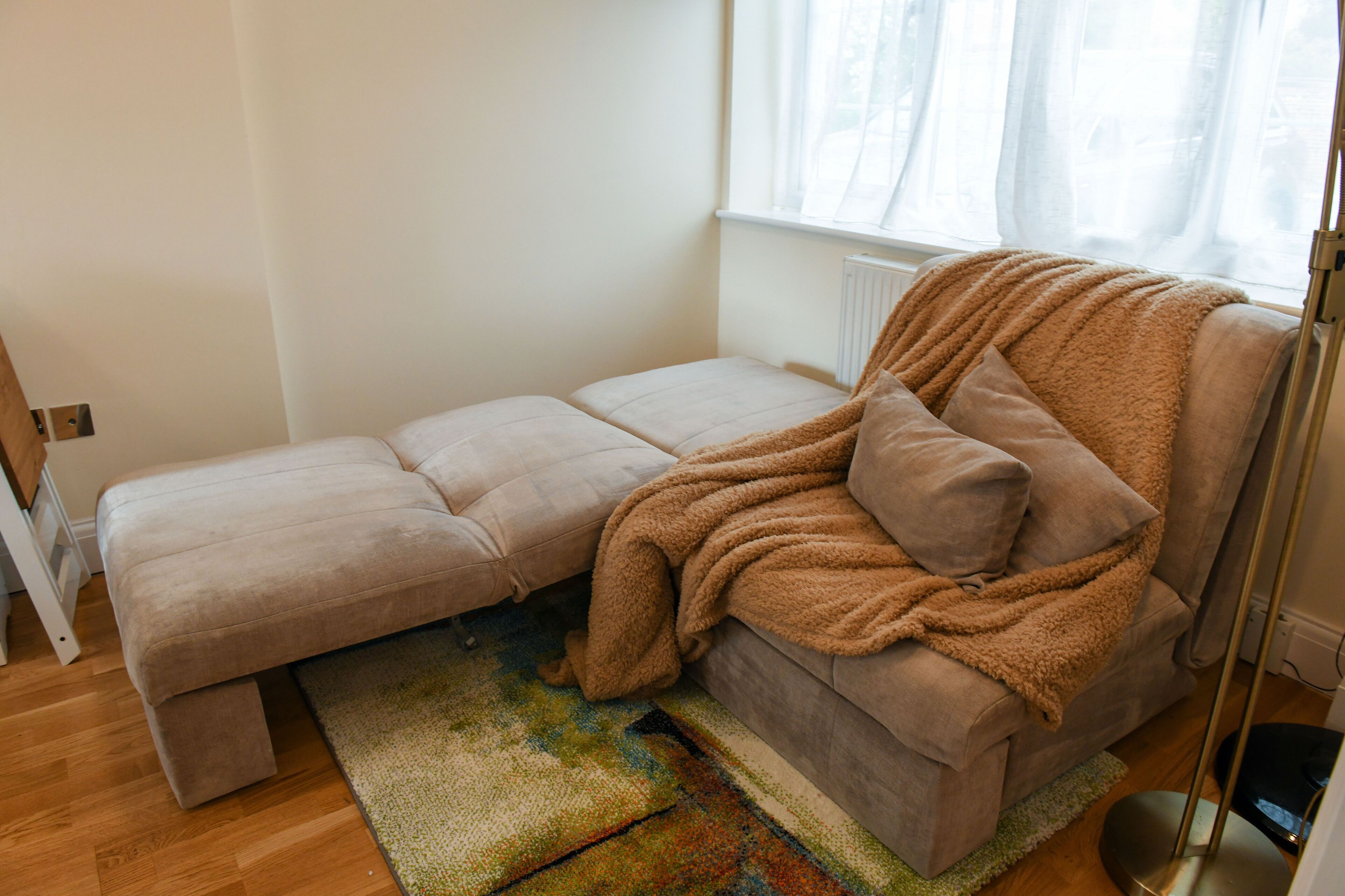 A cozy room with a sofa bed, a patterned rug, and a radiator.