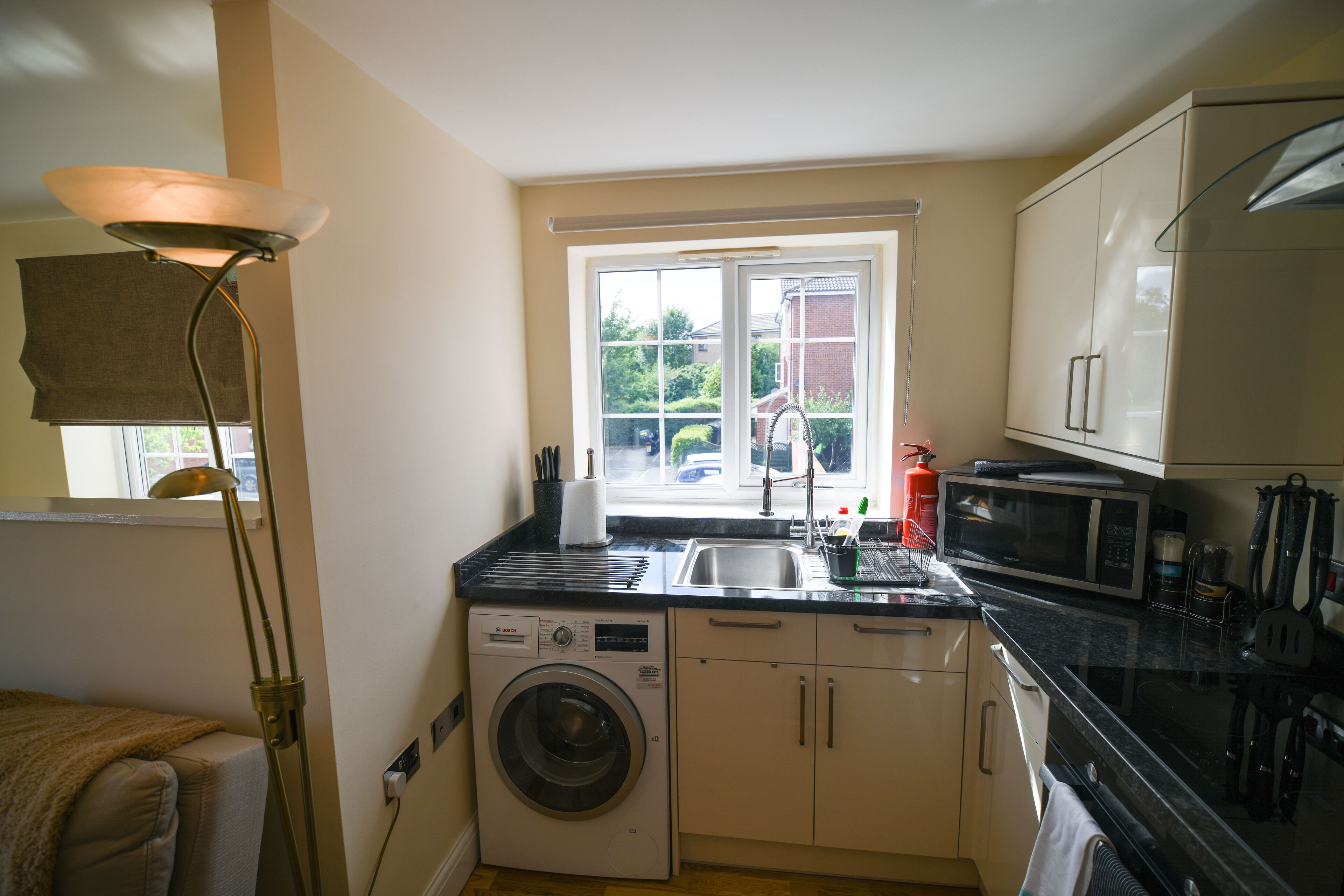 A compact kitchen with a washing machine, a microwave, and a sink.