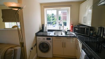 A compact kitchen with a washing machine, a microwave, and a sink.