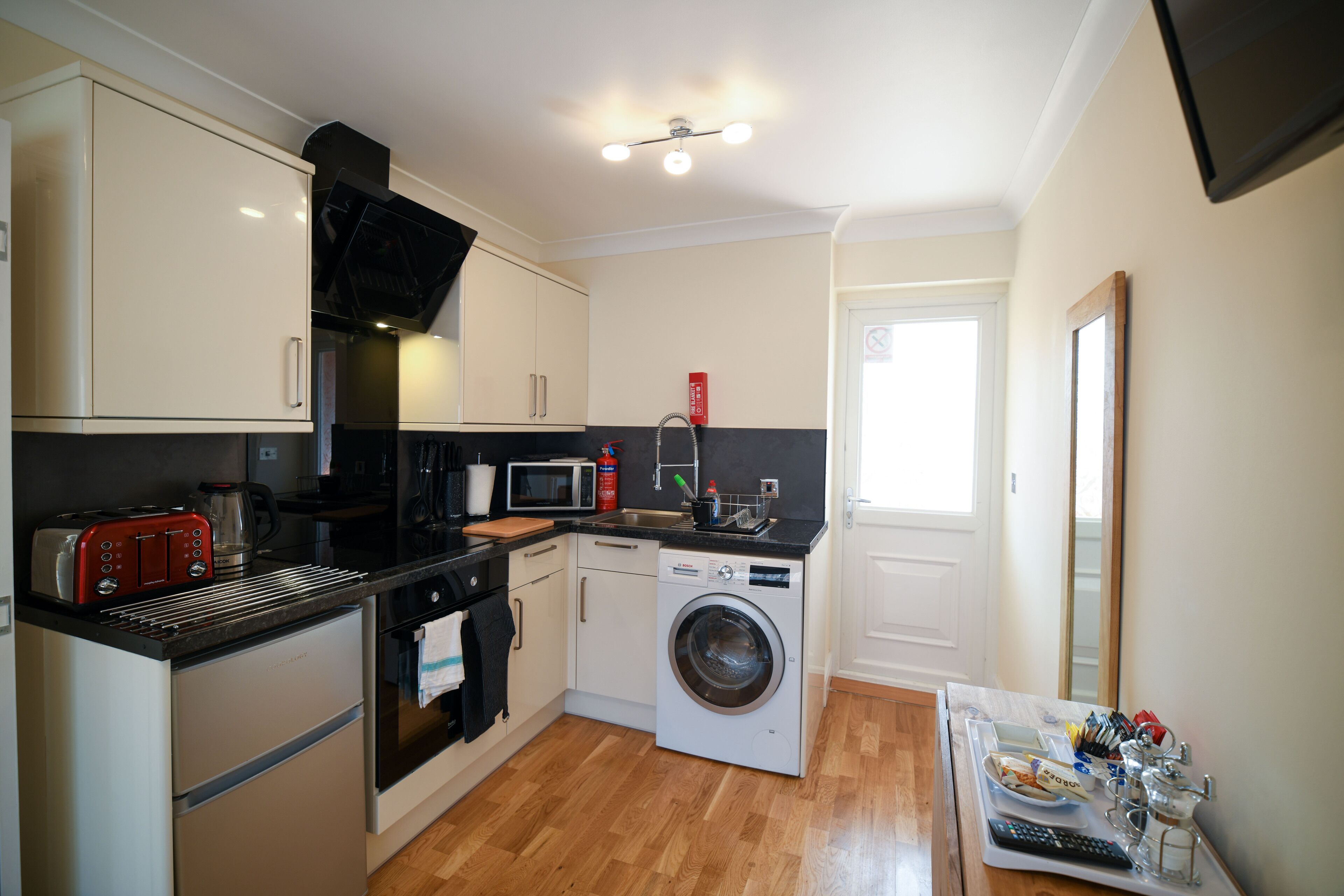 A compact kitchen with a microwave, toaster, oven, and washing machine.