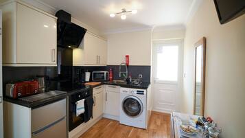 A compact kitchen with a microwave, toaster, oven, and washing machine.