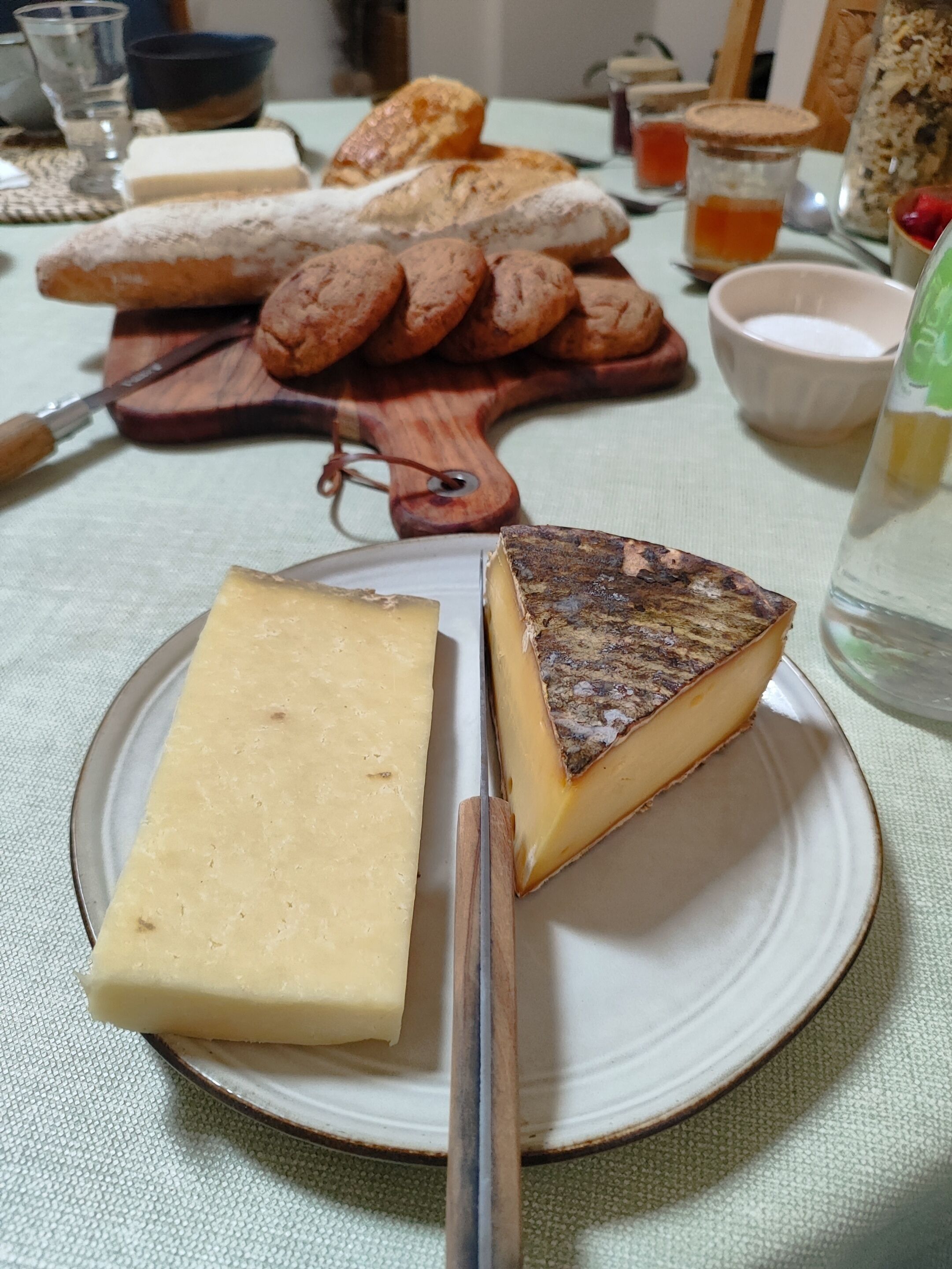 Un plato con una rebanada de queso y un trozo de pan sobre un mantel.