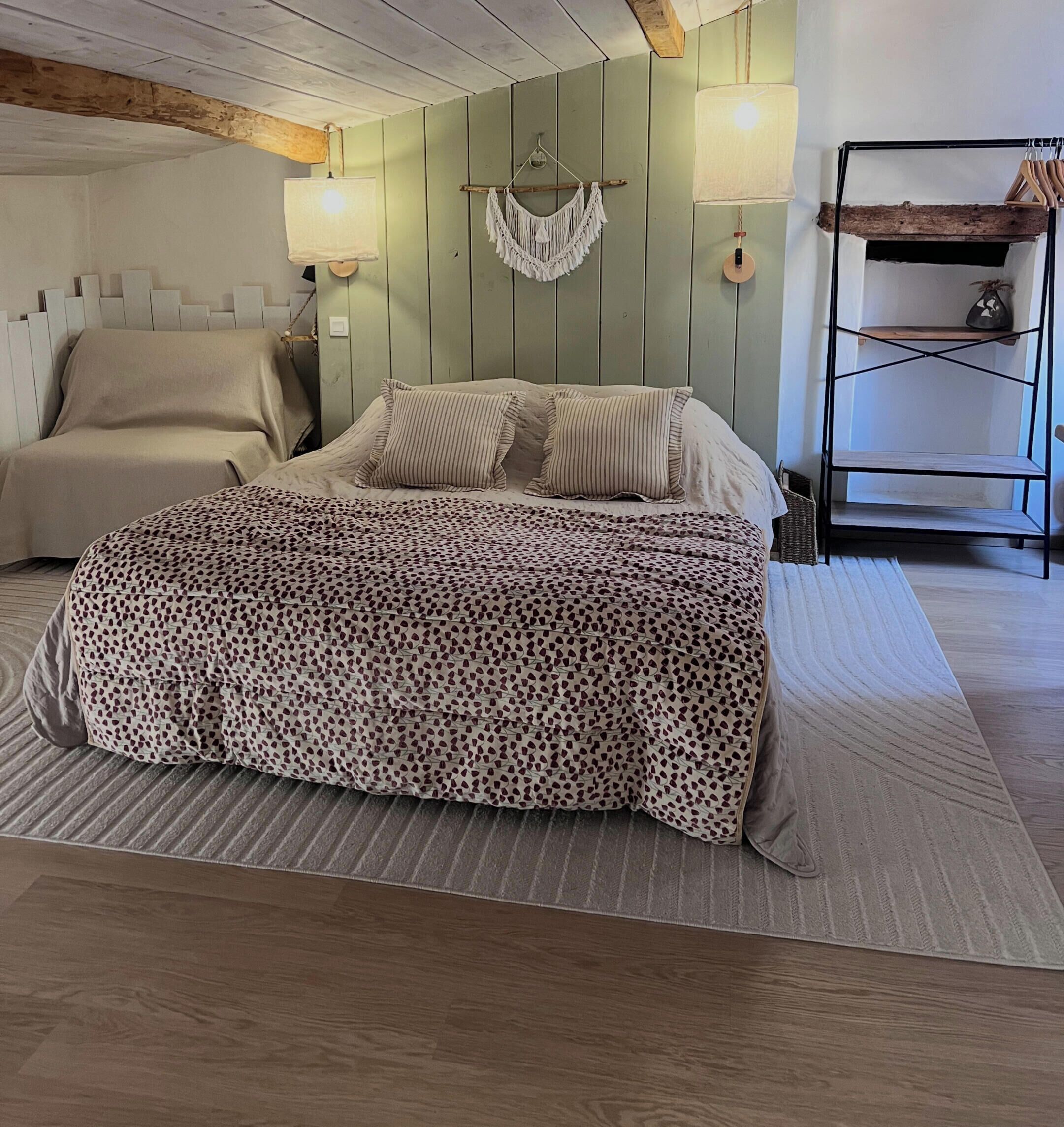 A bedroom with a bed, a hanging macrame wall decoration, and a wooden shelf unit.