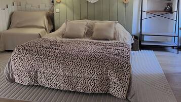 Een slaapkamer met een bed, een macramé wanddecoratie en een houten plankunit.
