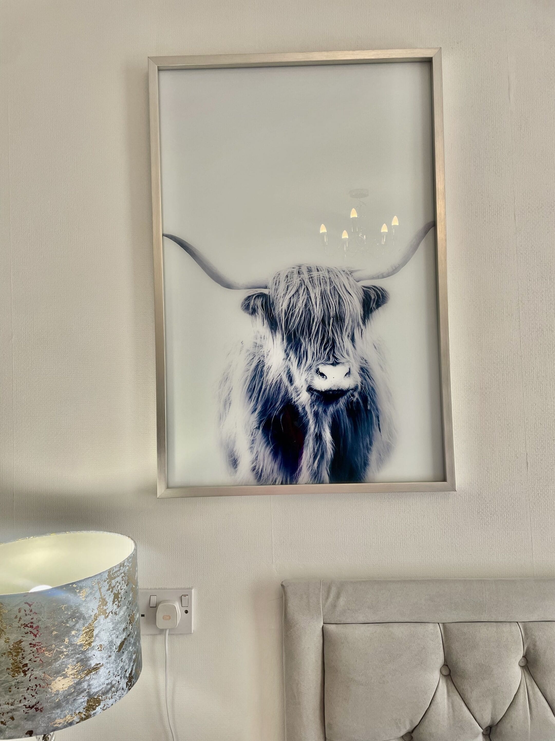A framed artwork of a yak on a wall.