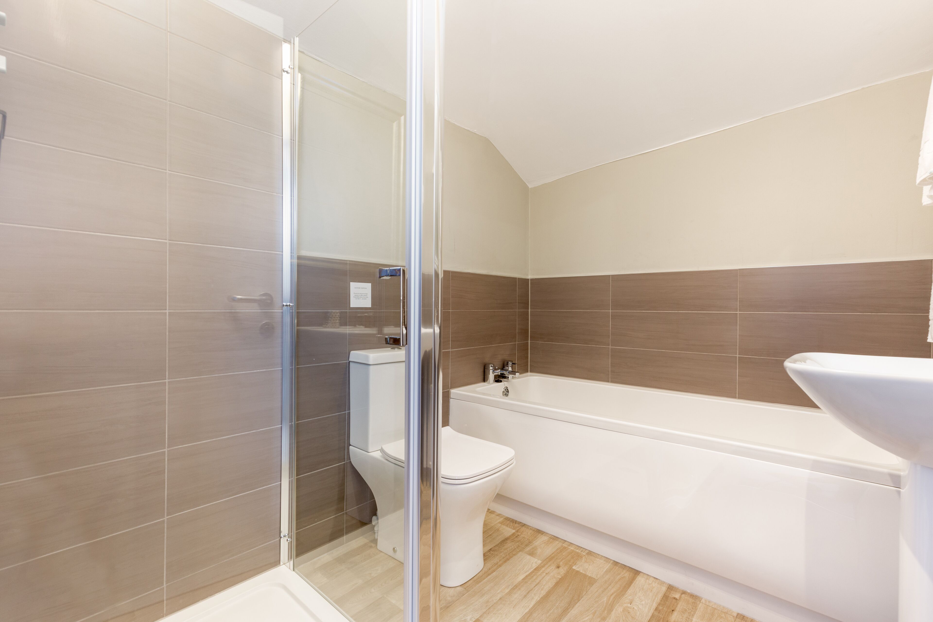 Un baño moderno con cabina de ducha de vidrio, inodoro blanco y bañera.