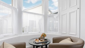 A room with a round table set for breakfast, two armchairs, and large windows with white shutters. - The Kirkstyle Hotel (Biggar)