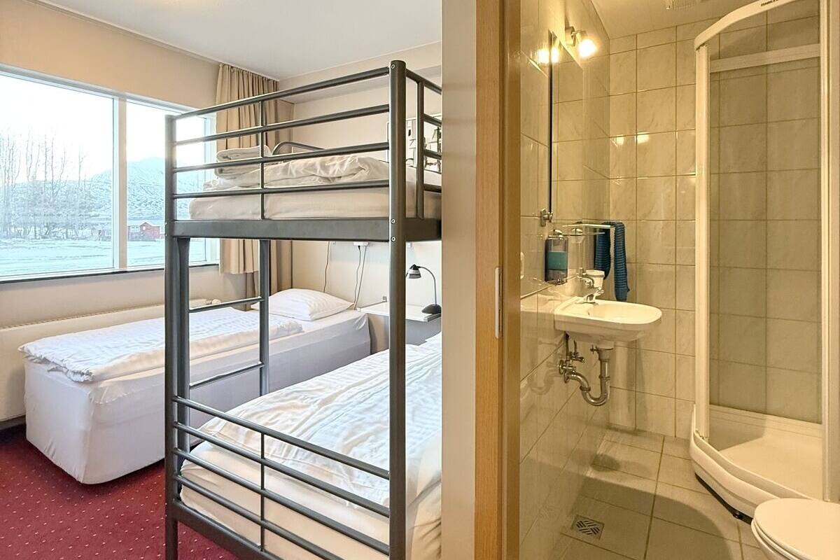 Ein Schlafraum mit Etagenbetten, einem Fenster, einer Dusche und einem Waschbecken.