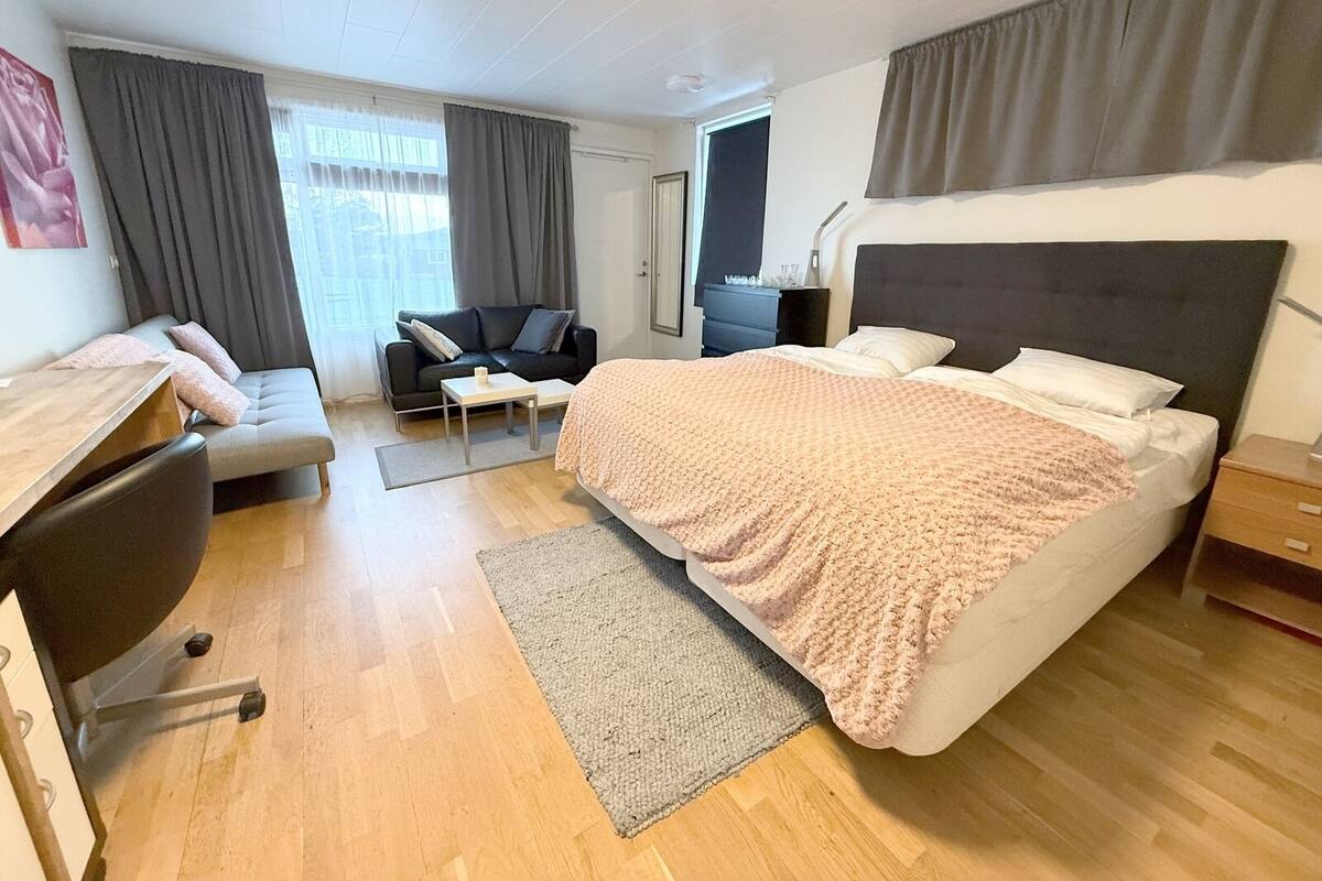 Ein modernes Hotelzimmer mit einem großen Bett, einem Schreibtisch, einer Couch und einem kleinen Tisch.