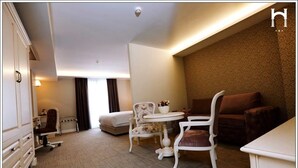 Une chambre d’hôtel comprenant un lit, un bureau, une chaise, une petite table et un canapé.