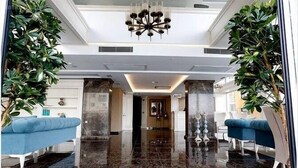 A spacious lobby with a polished marble floor, a chandelier, and blue upholstered seating. - Hanzade Park Hotel (Akçaabat)