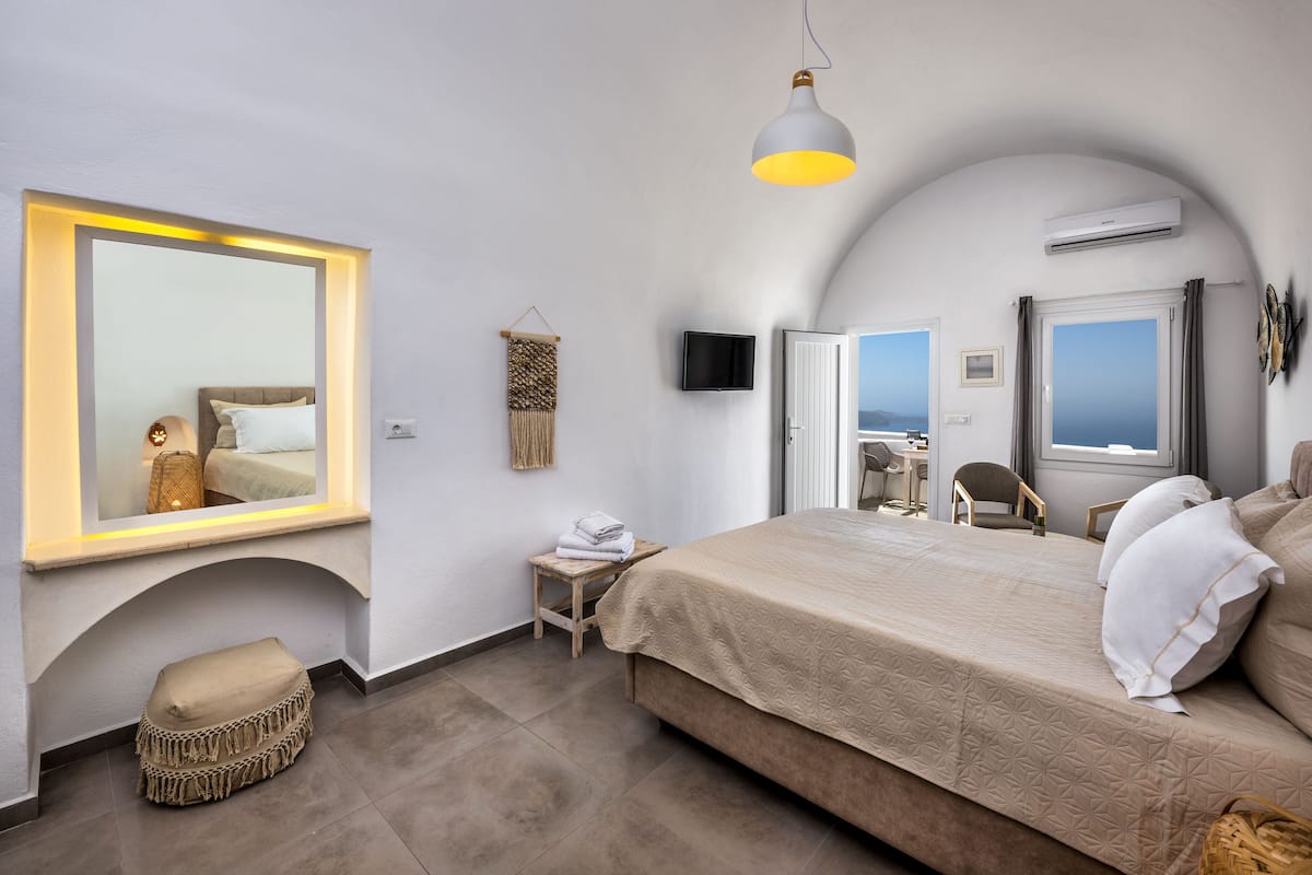 Une chambre avec un grand lit, une table de chevet, une chaise, un téléviseur et une fenêtre donnant sur un beau paysage.