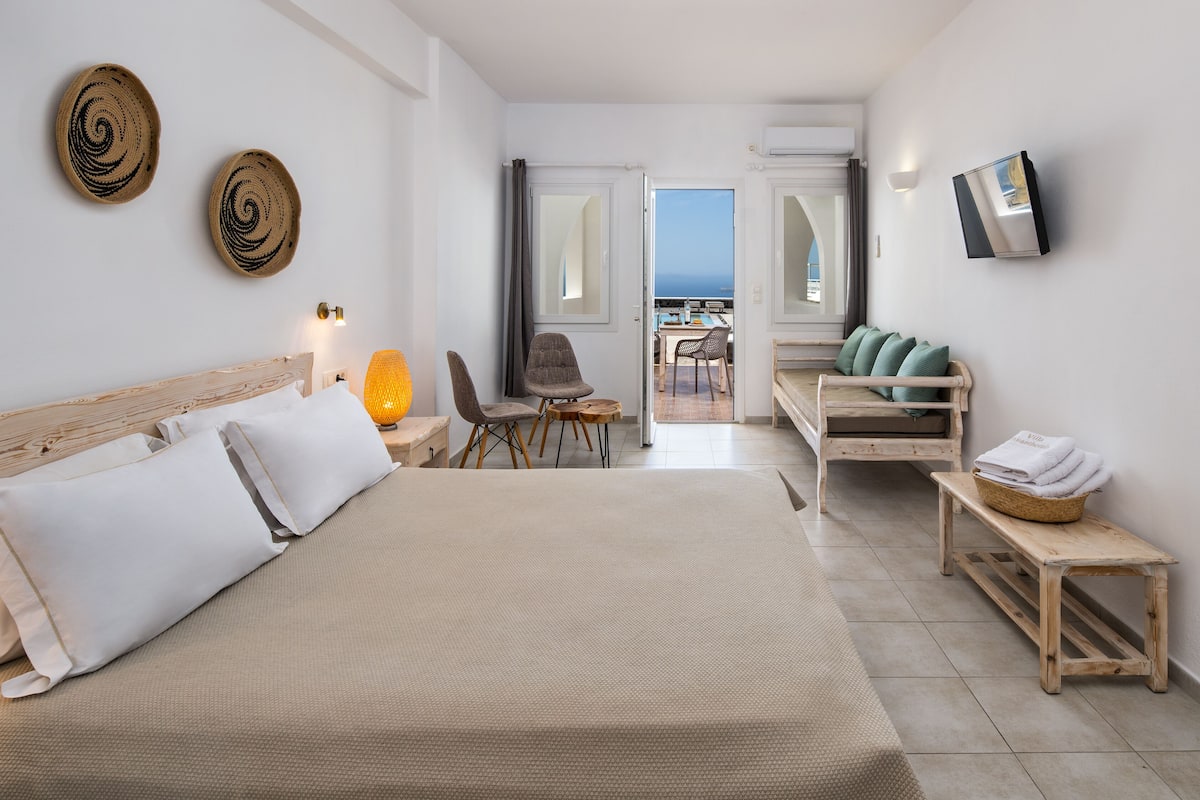 Une chambre d’hôtel avec un lit, un bureau, une chaise et une vue sur la mer.