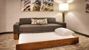 Een hotelkamer met een bed, een bank en een lamp.
