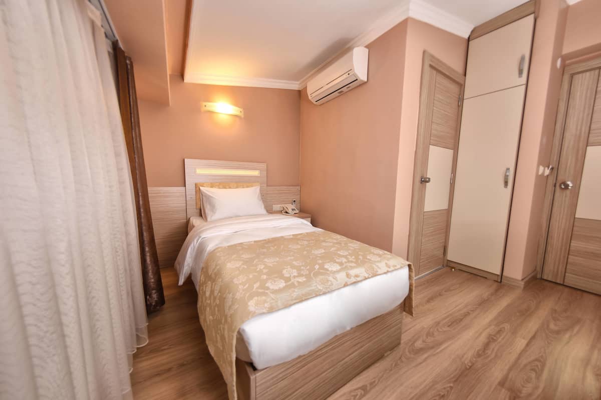 Un dormitorio con cama, armario, aire acondicionado y lámpara de noche.