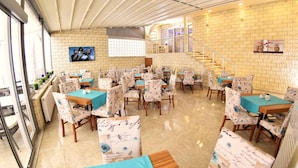 A dining area with multiple tables and chairs, a staircase, and a brick wall. - Sonerbey Otel (Ordu)