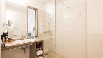 A modern bathroom with a glass-enclosed shower, a sink with a mirror, and a towel rack.