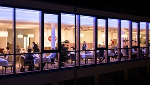 A well-lit indoor dining area with multiple tables and chairs, large windows, and a Christmas tree. - Siebenquell GesundZeitResort (Weissenstadt)