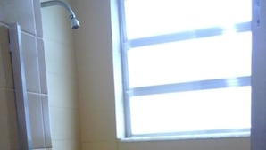 A small, enclosed shower area with a window, tiled walls, and a door. - Center Hotel Barra (Rio de Janeiro)