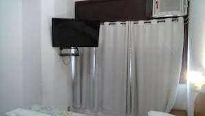 A room with a bed, a television mounted on the wall, and a curtain. - Center Hotel Barra (Rio de Janeiro)