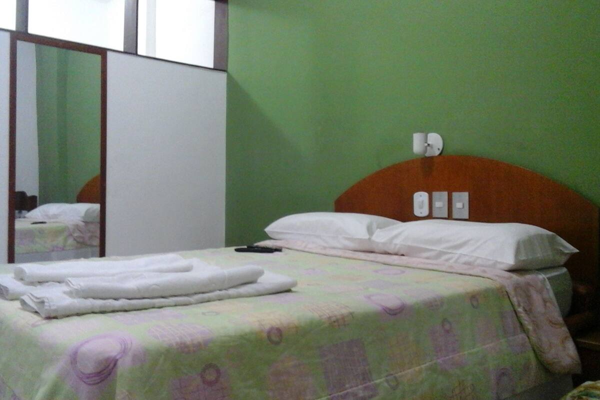 Un dormitorio con cama, mesita de noche, espejo y armario.