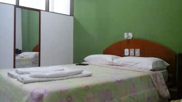 Un dormitorio con cama, mesita de noche, espejo y armario.