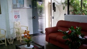A lobby with a red sofa, a coffee table with a plant, and a wall-mounted sign. - Center Hotel Barra (Rio de Janeiro)