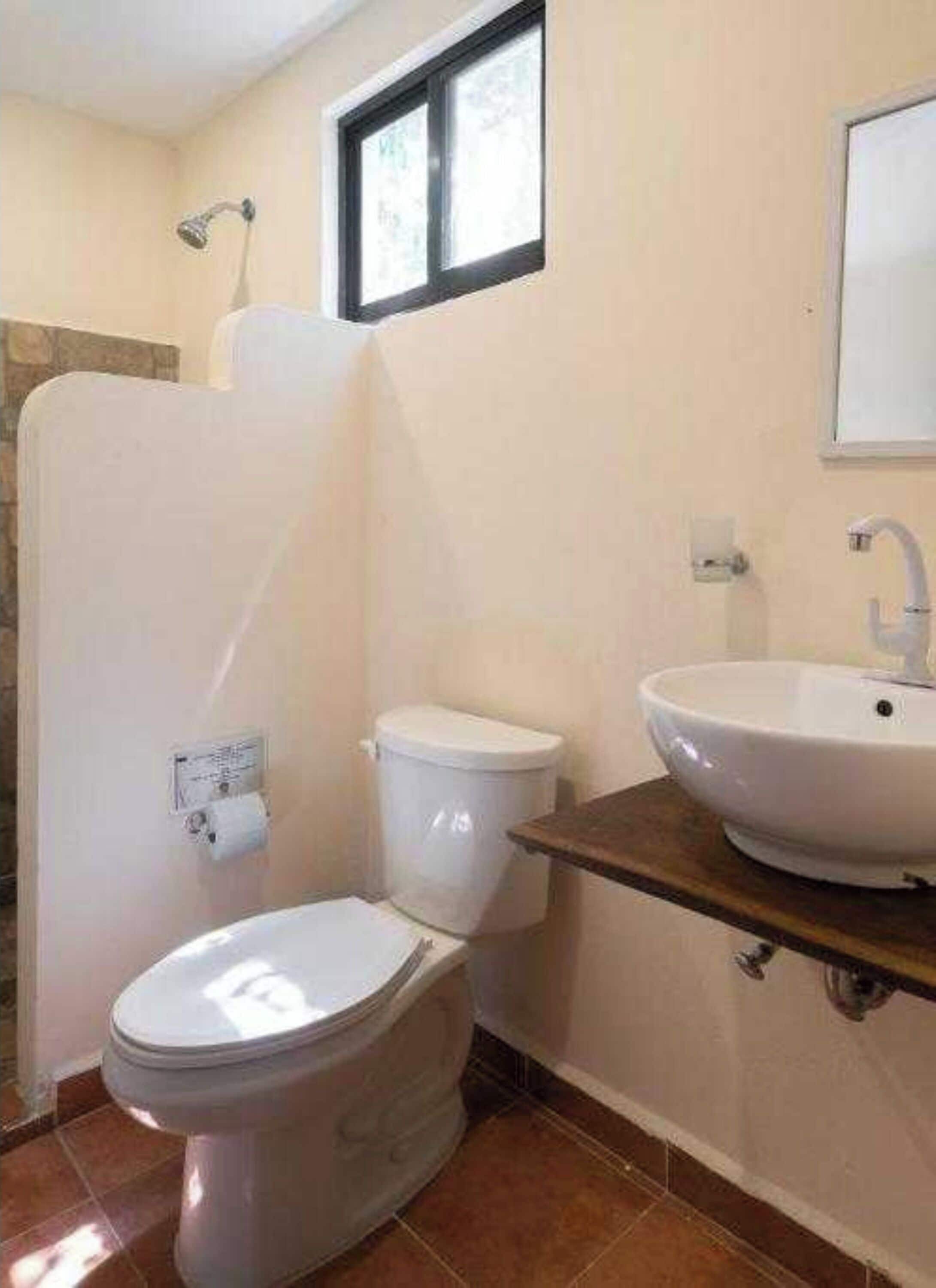 Un baño con inodoro, lavamanos y ducha.