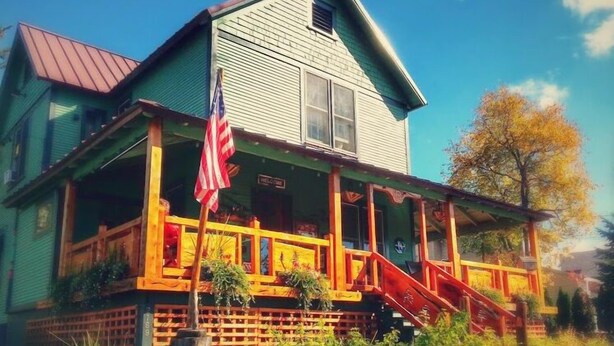 Een huis met twee verdiepingen, een veranda, een rode trap en een Amerikaanse vlag.