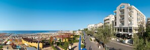 A coastal hotel with multiple balconies, a beach view, and a spacious outdoor area with umbrellas. - Hotel Prestige (Cattolica)