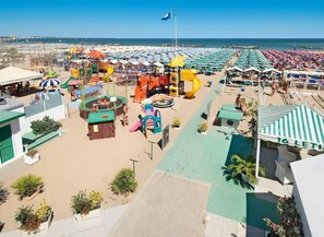 A beachside resort with a children's play area, beach umbrellas, and a pool. - Hotel Prestige (Cattolica)