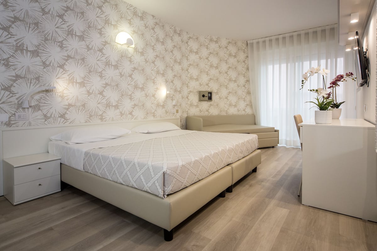 Une chambre moderne avec un lit, des tables de chevet, un canapé et un bureau.