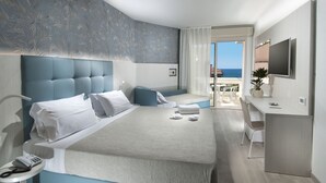 Une chambre d’hôtel moderne avec un grand lit, un bureau et une vue sur la mer.