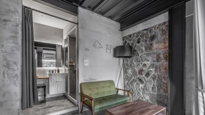 A modern living room with a green sofa, a wooden coffee table, and a stone accent wall. - Jiufen The Ore Inn (New Taipei City)
