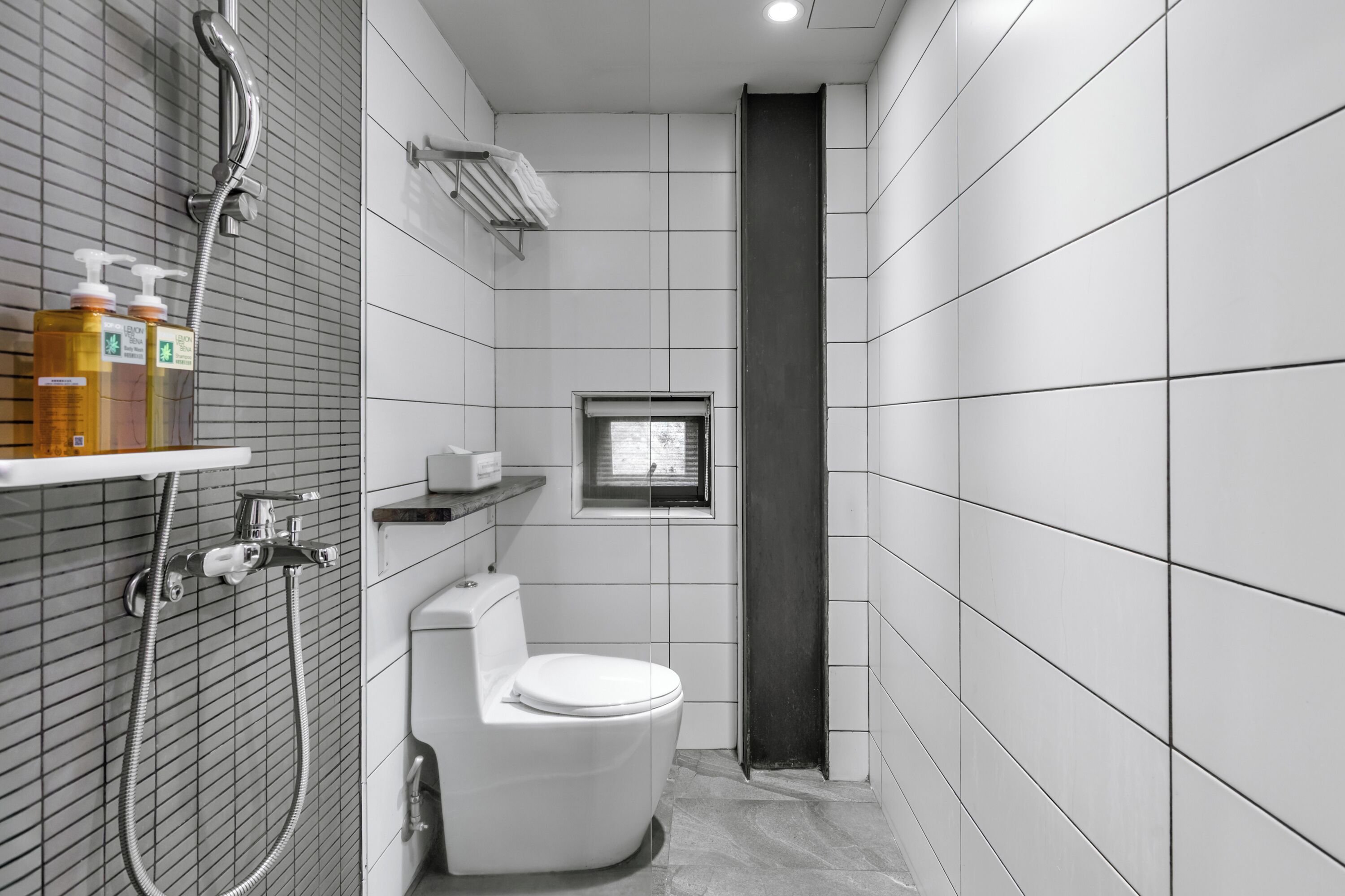 A modern bathroom with a toilet, shower, and a window.