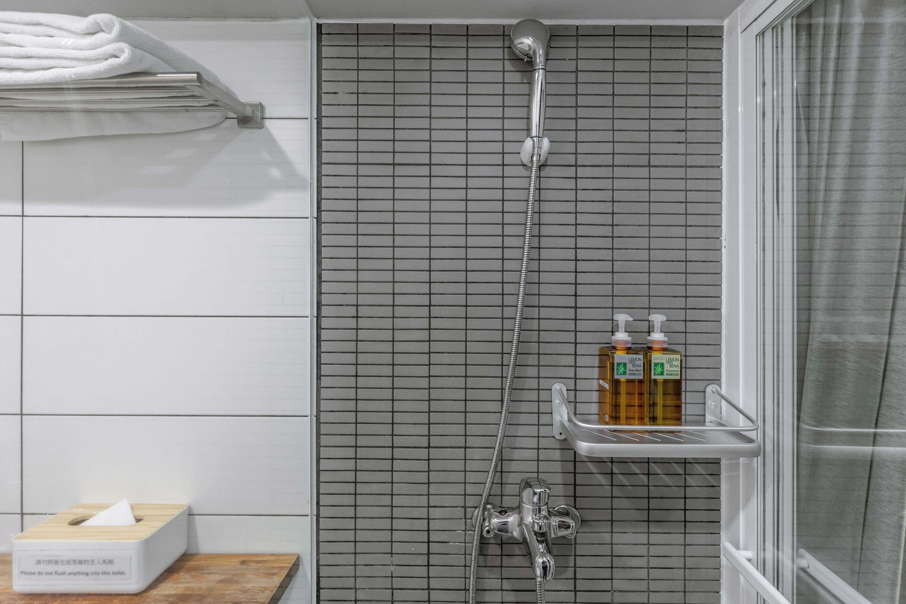 Een badkamer met een douche, een handdoekhouder, een zakdoosje en een zeepdispenser.