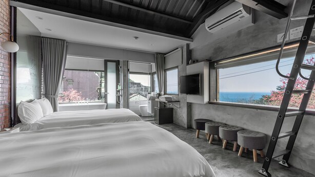 A modern hotel room with two beds, a balcony, a TV, and a view of the sea. - Jiufen The Ore Inn (New Taipei City)