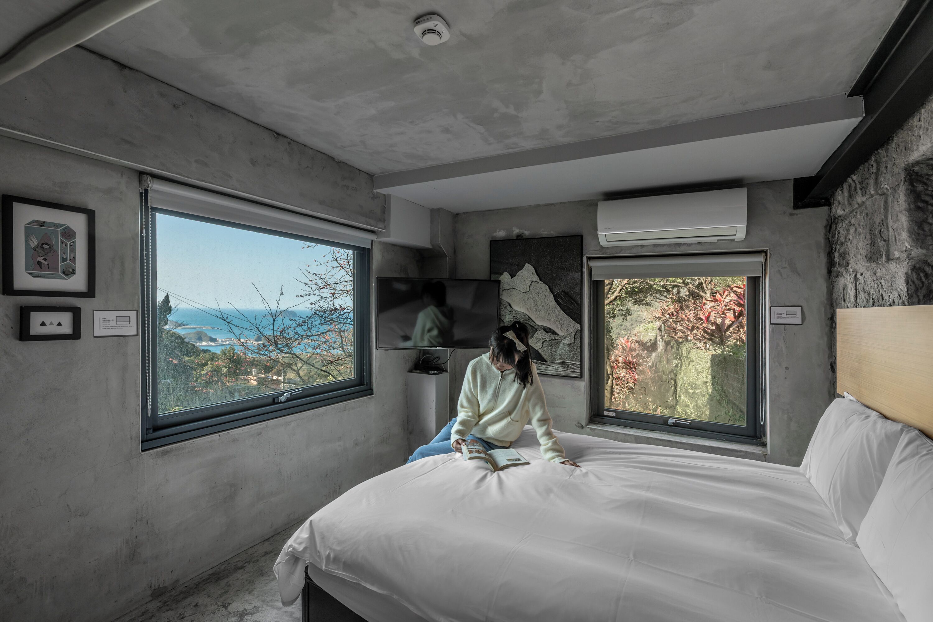 A bedroom with a large bed, two windows, and a view of the outdoors.
