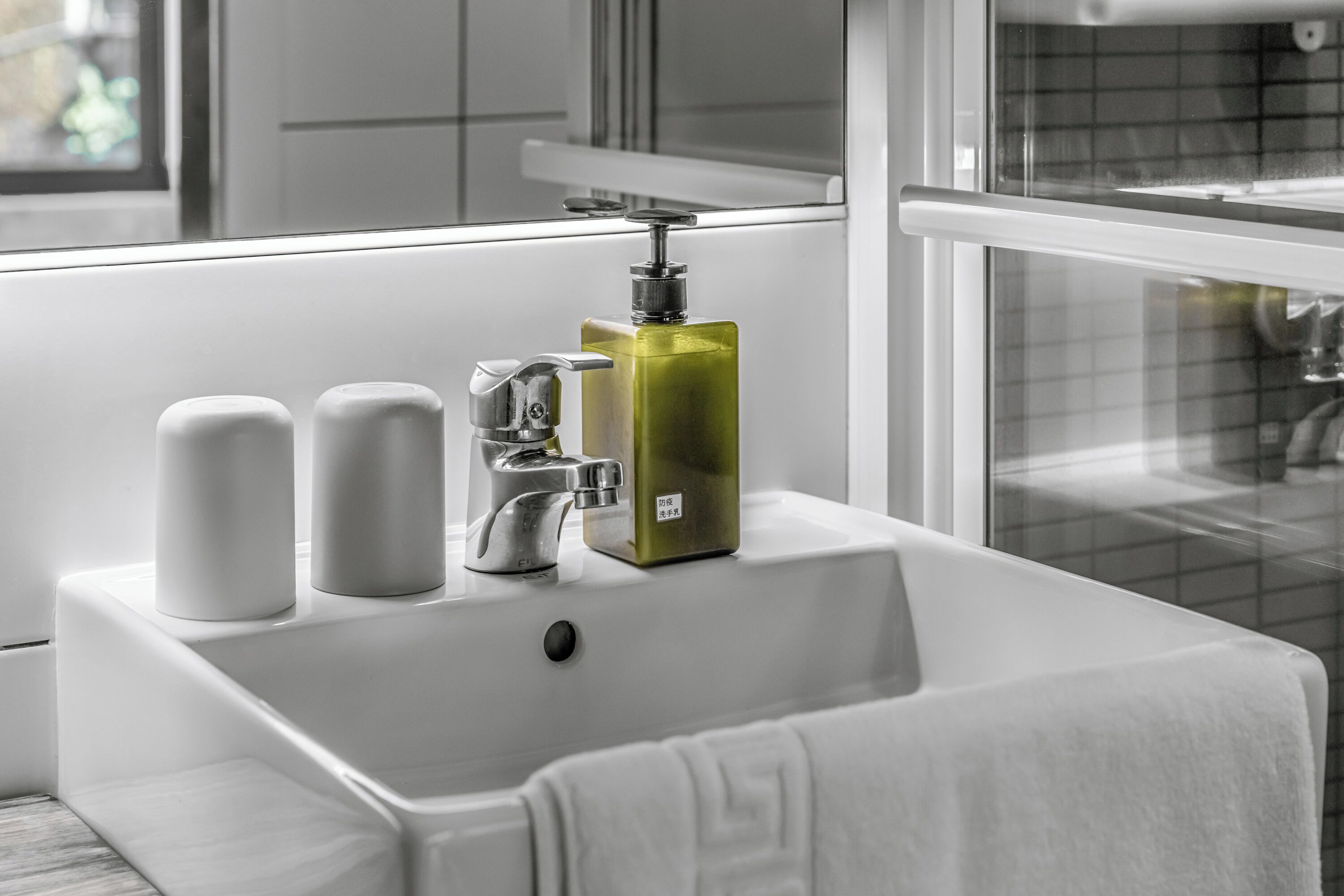 A bathroom with a white sink, two soap dispensers, and a green soap bottle.