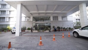 Ein Hotel mit Eingang, Glastür, Blumentöpfen und einem Sicherheitsdienst.